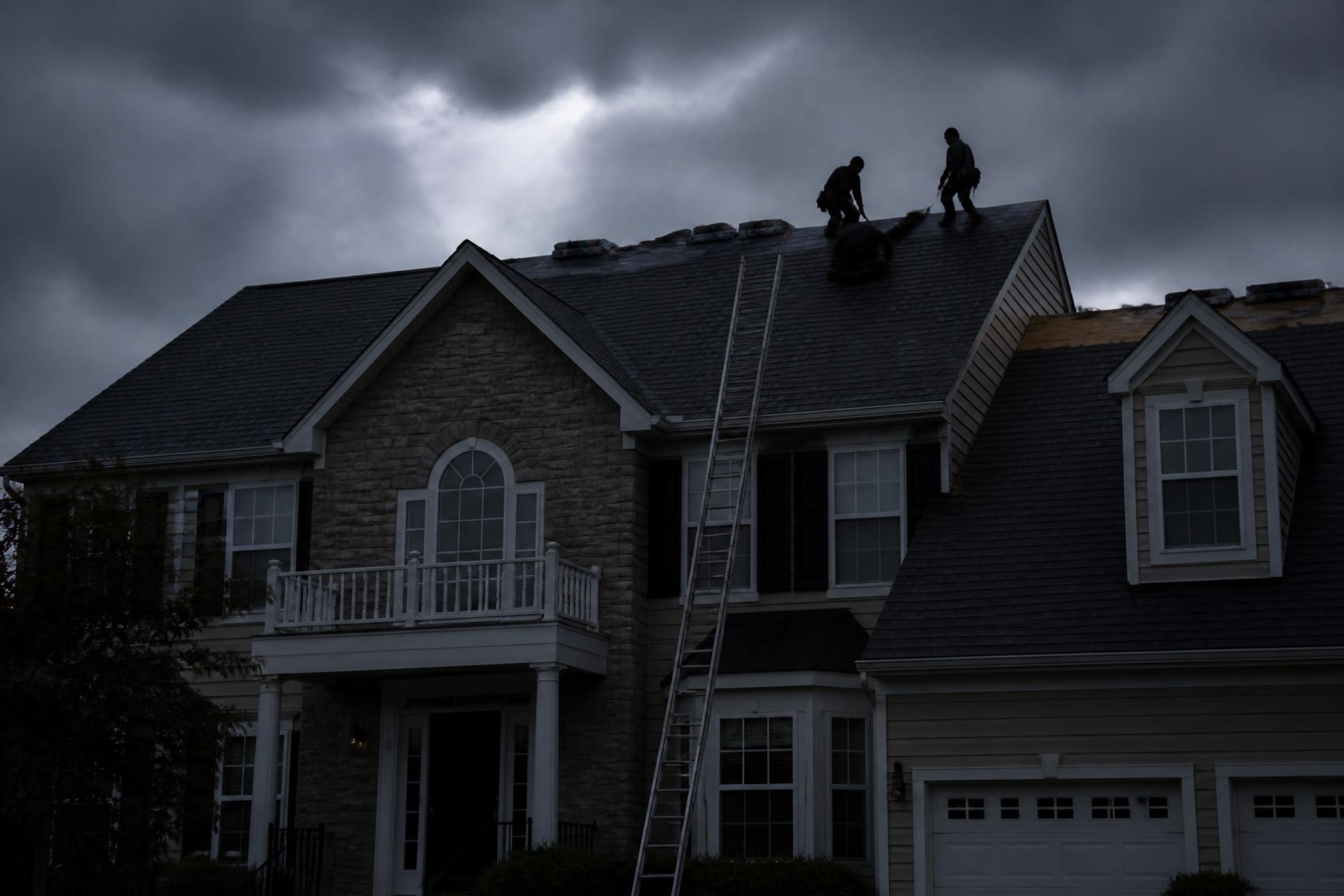 Roofing crew replacing shingles on a New Jersey home under a storm sky